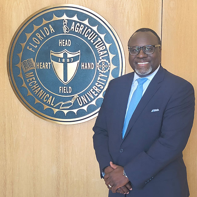 Marcus Shaw, CEO of AltFinance standing in front of a FAMU seal on an oak panel wall.